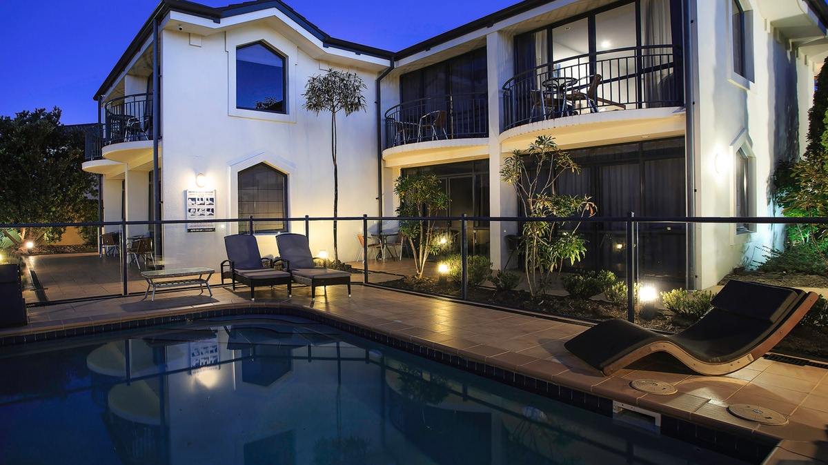 delorenzos-night-time-with-pool a house with trees in the background