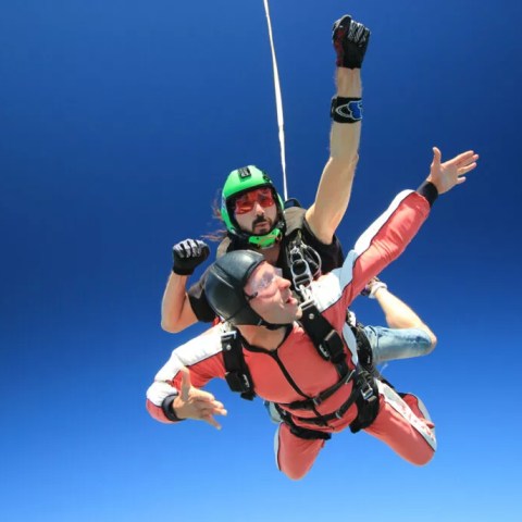 Tandem Skydivers confidently posing in the camera during a jump.