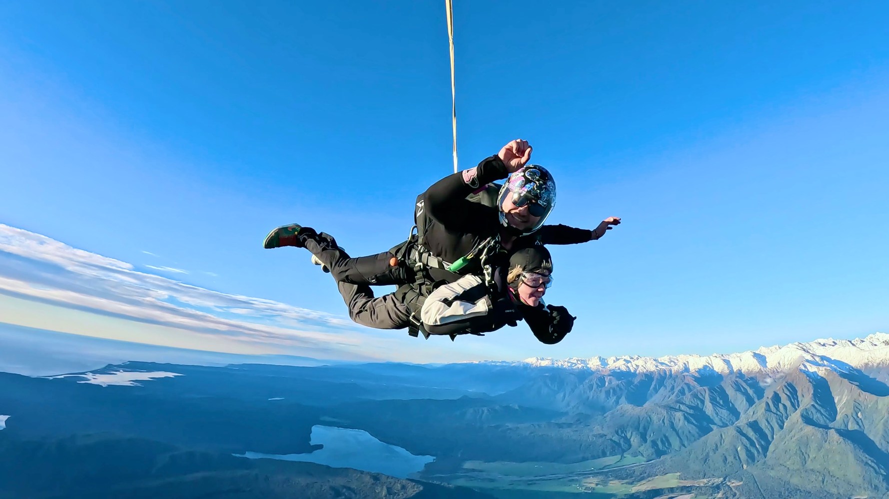 helicopter tandem skydivers free fall over mountains and coastline