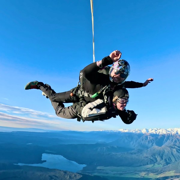 helicopter tandem skydivers free fall over mountains and coastline