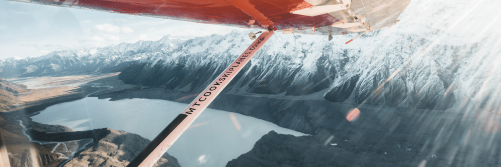 View of snowy mountains and lake from small plane window