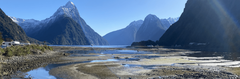 Snow-capped mountains by a lake with a clear blue sky.