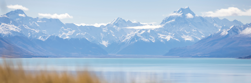 Snow-capped mountains over a tranquil blue lake under a clear sky.