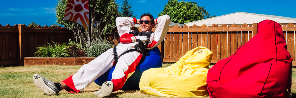 Person in colorful outfit relaxing on bean bags in sunny backyard.