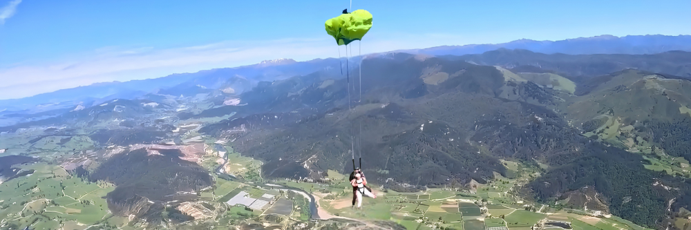Parachutist descending over a scenic mountain landscape.