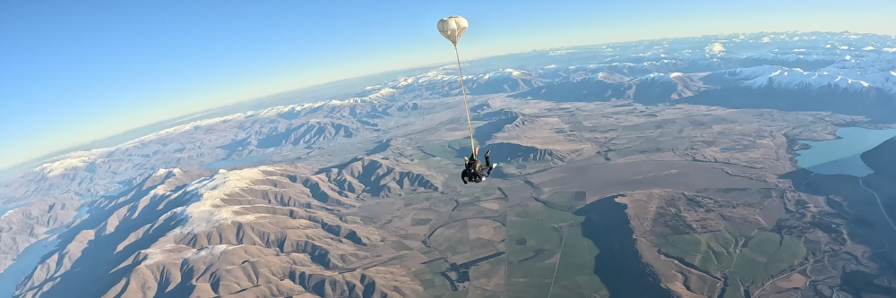 Parachute over mountainous landscape with clear skies.
